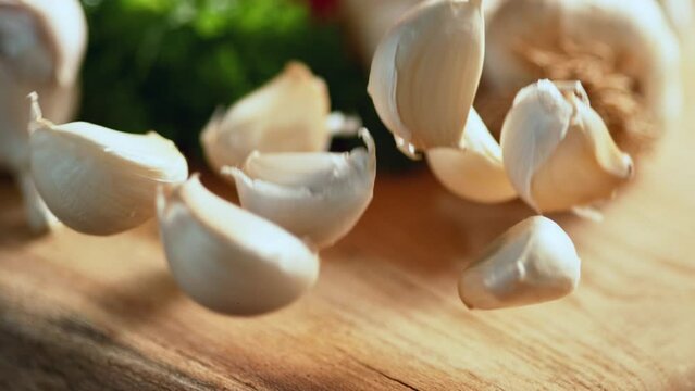 Garlic falling in front of the camera on wooden floor in slow motion and scattering around. Macro, 4K, Phantom Camera, Super Close Up.