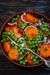 Healthy salad with carrots, green peas and blue onions. Vegan diet.