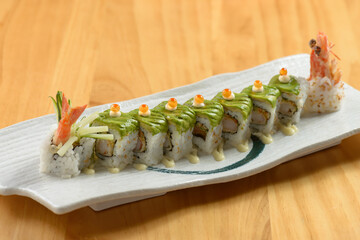 Sushi roll set green Dragon in white tray on wooden background top view