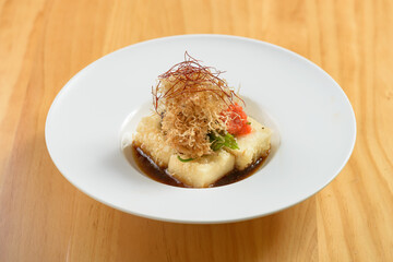 Japanese Food Agedashi Tofu served in flavorful tsuyu sauce in a white bowl top view on wood background