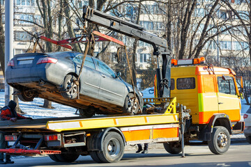 The work of a car tow truck on a city street on a winter sunny day.