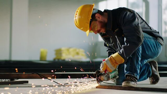 In the large building construction in front of the camera constructor worker using disc welding machine to cut some metals and creating the big sparks