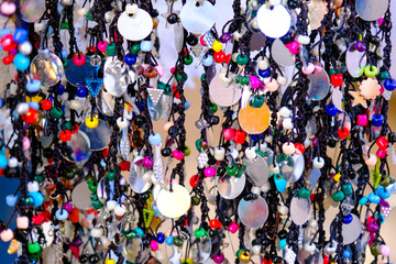 Colorful handmade ethnic jewelry or bracelet charms lined up on a rope hanger in woman producer bazaar in Odemis, Izmir. Many modern style accessories in different colors.