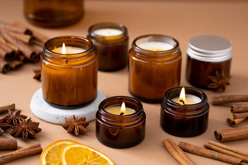 Obraz na płótnie Canvas A set of different aroma candles in brown glass jars. Scented handmade candle. Soy candles are burning in a jar. Aromatherapy and relax in spa and home.
