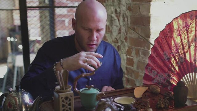 A man drinks green tea from a tea set in a tea room