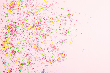 Colorful sprinkles on pink background, top view. Confectionery decor. Multicolor confectionery topping dressing. Festive background