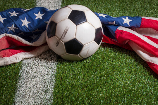 Soccer ball and American flag on grass field with white stripe