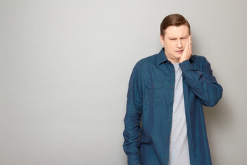 Portrait of unhappy man touching cheek and suffering from toothache