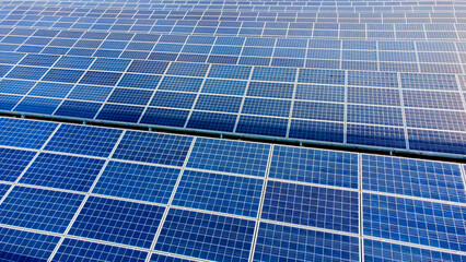 Aerial drone view flight over solar panels on sunny day close-up. Photovoltaic solar panel. Moving over solar panels with sun glare. Production of renewable alternative energy. Green ecological energy