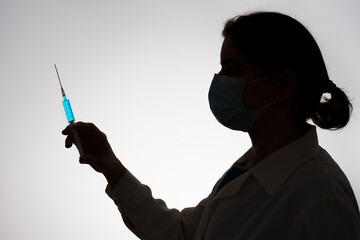 Silhouette of a doctor with syringe filled with blue liquid. Vaccination concept.