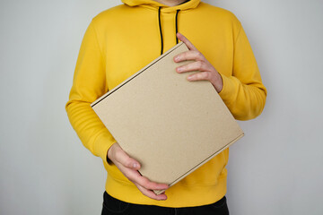 Man holds a paper box in his hand. Person with new package. Postal services, delivery. Kraft paper....