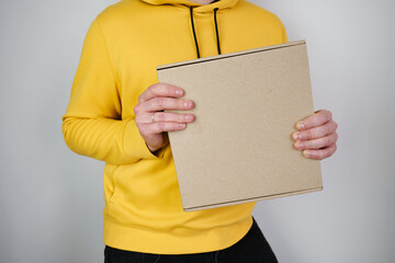 Man holds a paper box in his hand. Person with new package. Postal services, delivery. Kraft paper....