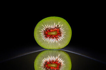 Slice of akiwi isolated in dark black background with reflection