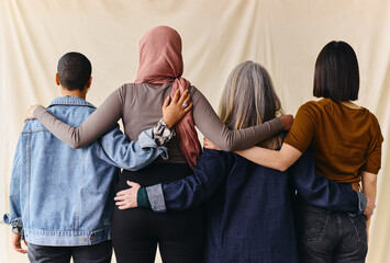 Rear view of four women with arms around each other in support of International Women's Day - obrazy, fototapety, plakaty