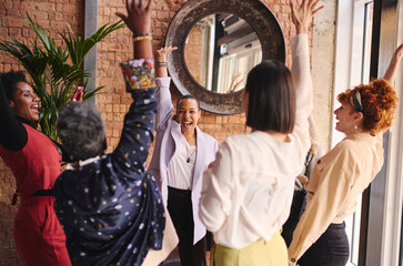 Multi ethnic mixed age range businesswomen cheering in support of International Women's Day