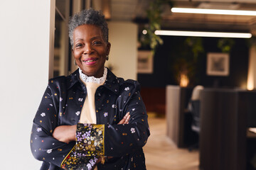 Portrait of confident senior black woman smiling and looking at camera with arms folded - Powered by Adobe
