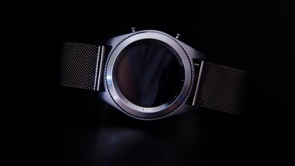 Silver elegant smart watch with a metal bracelet in the dark abstraction