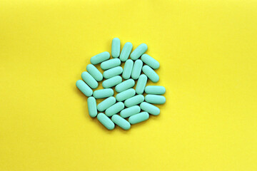 A group of blue pills on a yellow background. Vitamins and supplements 