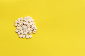 Obraz na płótnie Canvas White pills on a yellow background. Medicine