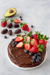 Vegan date cake without sugar. Cream of avocado with cocoa. Garnished with strawberries and blueberries. Proper nutrition concept.