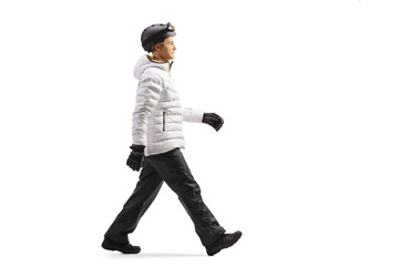 Full length profile shot of a young man in winter clothes walking