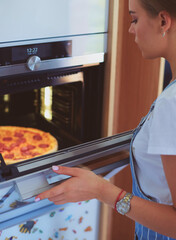 Happy young woman cooking pizza at home