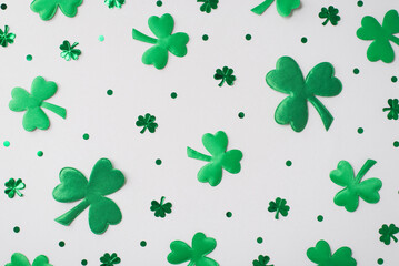 Top view photo of the green confetti different size and shades in shape of clovers and small dots...