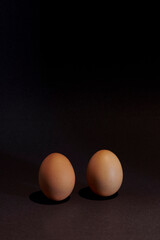 Two brown eggs with a black backdrop