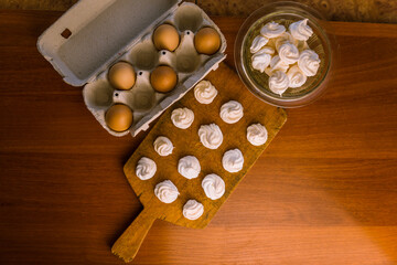 Delicious crispy homemade egg meringue, prepared with love on a wooden background, crunchy dessert for coffee or tea.