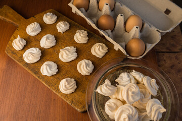 Delicious crispy homemade egg meringue, prepared with love on a wooden background, crunchy dessert for coffee or tea.