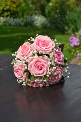 wedding bouquet of pink roses against a blurry background of green leaves