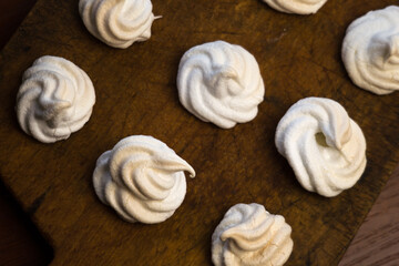 Delicious crispy homemade egg meringue, prepared with love on a wooden background, crunchy dessert for coffee or tea.