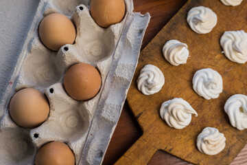 Delicious crispy homemade egg meringue, prepared with love on a wooden background, crunchy dessert for coffee or tea.