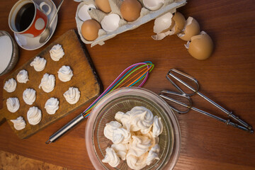 Delicious crispy homemade egg meringue, prepared with love on a wooden background, crunchy dessert for coffee or tea.