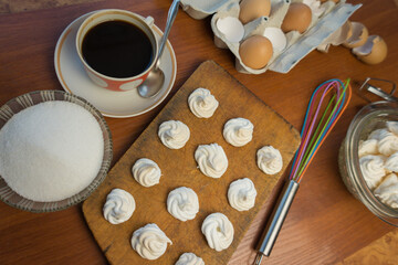 Delicious crispy homemade egg meringue, prepared with love on a wooden background, crunchy dessert for coffee or tea.