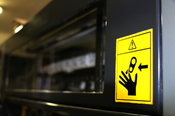 selective focus Warning label affixed to printing platen covers in a printing house. Careful hands can get stuck. danger of breaking fingers when the machine is in print. Work safety	
