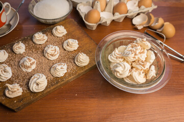 Delicious crispy homemade egg meringue sprinkled with grated dark chocolate, prepared with love on a wooden background, crunchy dessert for coffee or tea.
