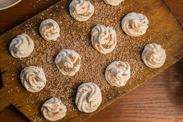 Delicious crispy homemade egg meringue sprinkled with grated dark chocolate, prepared with love on a wooden background, crunchy dessert for coffee or tea.
