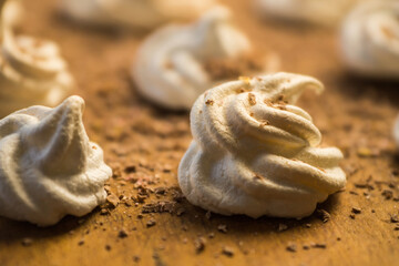 Delicious crispy homemade egg meringue sprinkled with grated dark chocolate, prepared with love on a wooden background, crunchy dessert for coffee or tea.
