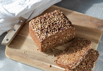 Wholemeal rye bread with sunflower seeds on cutting board.