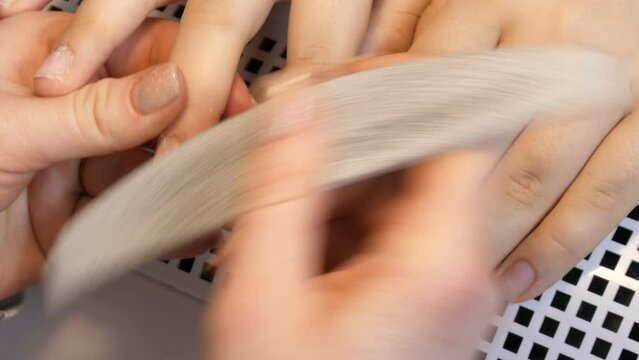 The manicurist files the shape of the nails with a special nail file. Special manicure tools polish on nails at home close up view