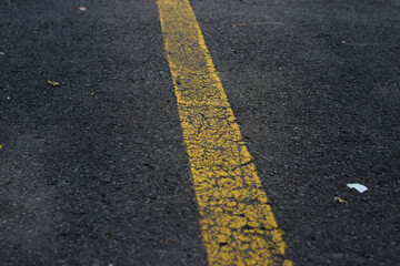 Fototapeta premium Defocus abstract background with yellow lines on cracked asphalt road in a parking lot. Cracked Asphalt background with yellow line