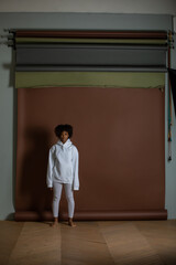 African american woman in a white hoodie and leggings stands on a brown background. Mock-up.