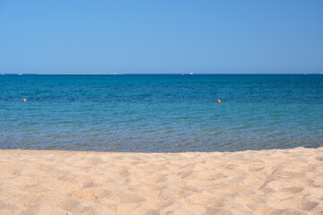 Seascape with surface of blue sea water with small ripple waves crashing on yellow sandy beach. Travel and vacations concept