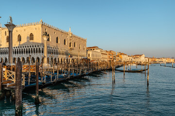 Venice,Italy.Embankment and famous Doges Palace on sunny day,canal and gondolas.Venetian city lifestyle.Architecture and landmark of Venezia.Popular tourist destination.Water transport,old houses