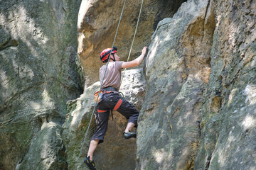 Strong male climber climbing steep wall of rocky mountain. Sportsman overcoming difficult route. Engaging in extreme sports hobby concept