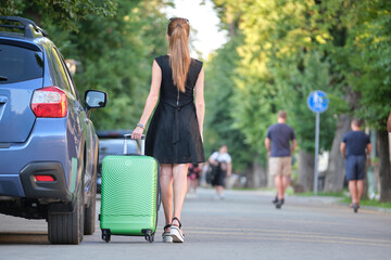 Young woman walking down the street with suitcase bag. Travelling and vacations concept