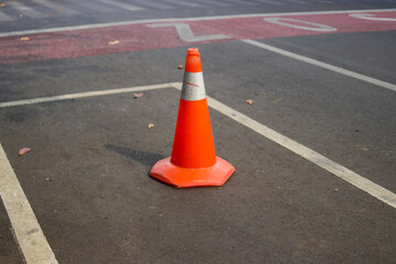 Traffic cone with white and orange stripes on gray asphalt in a shopping center parking lot