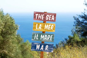 wooden placard signal with the sea written in several languages , focus in foreground