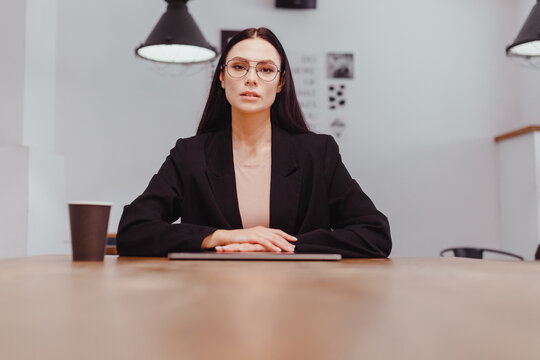 portrait of serious dissatisfied lady boss with stern look sitting at negotiating table